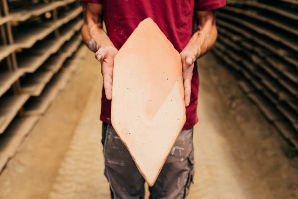 Uno de los maestros artesanos de todobarro muestra una baldosa de barro secada al sol