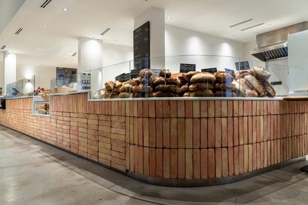 Expositor de pan en forma curva cubierto de ladrillos de barro rústicos en tonalidad salmón